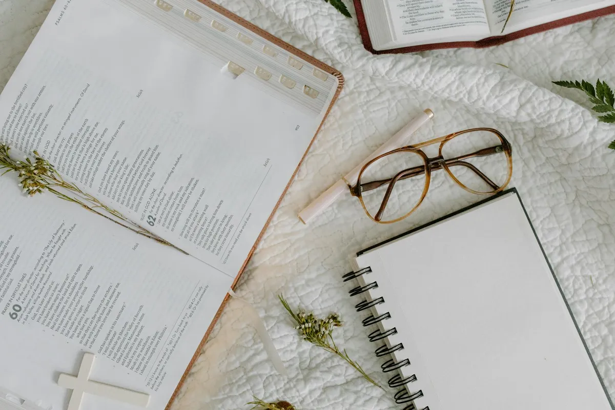 A Bible open beside a notebook with handwritten study notes