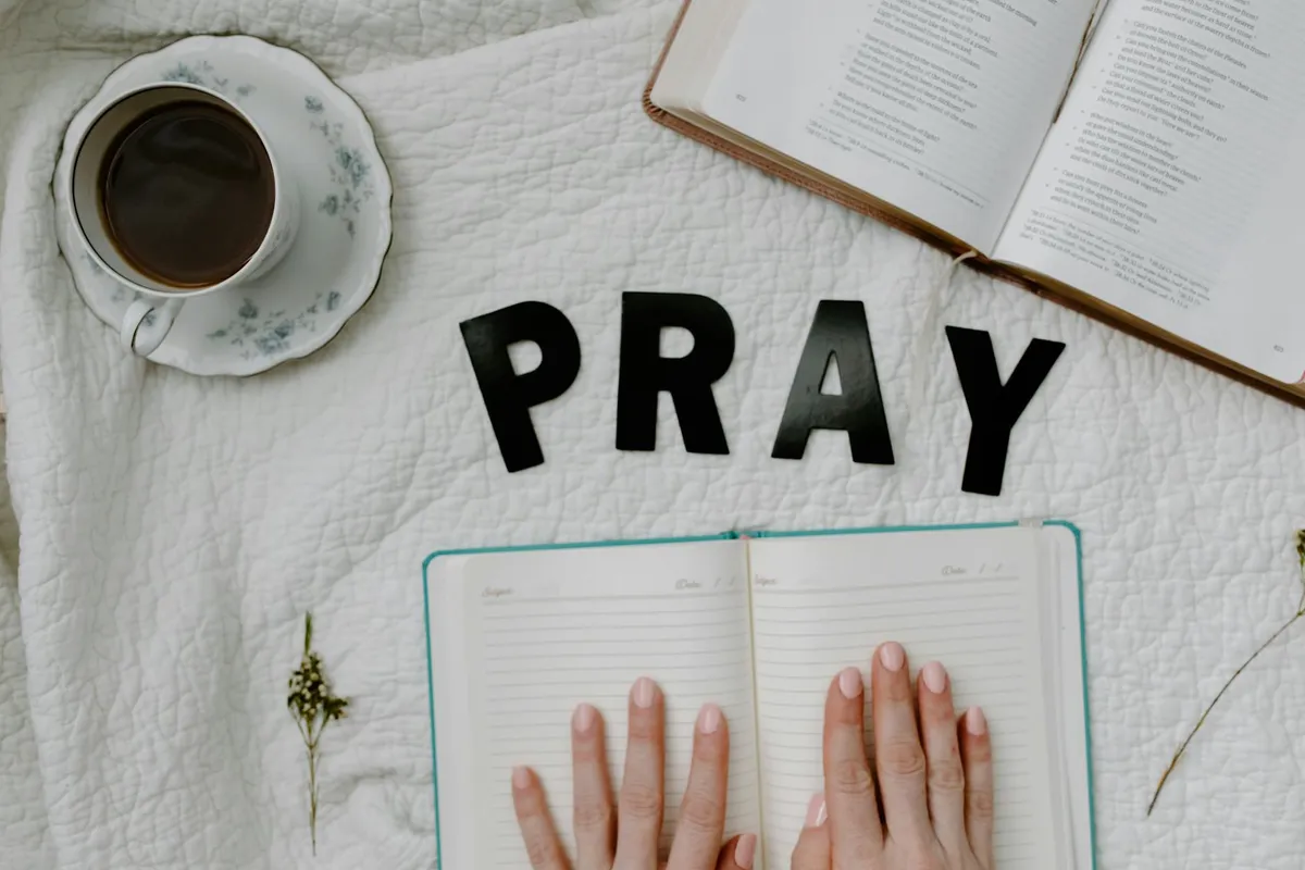 A prayer journal and coffee cup in morning light